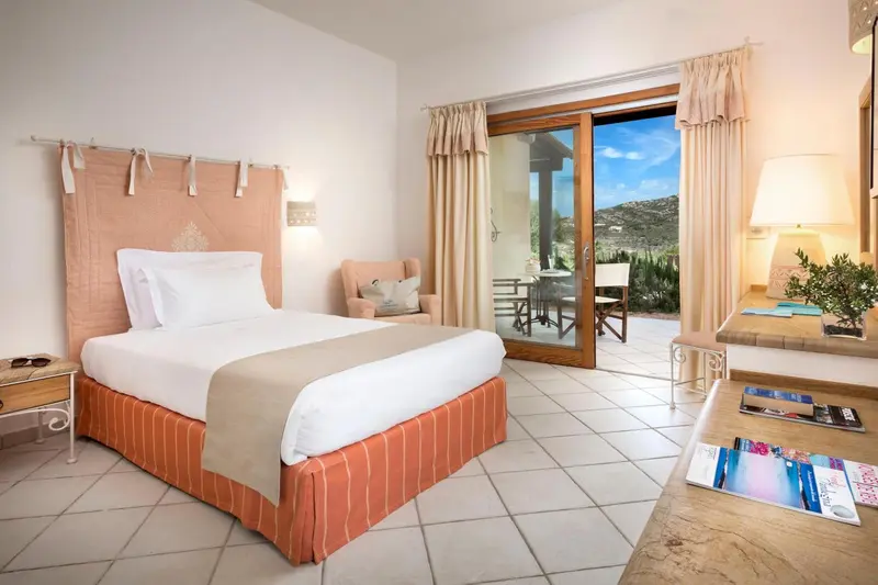 Chambre lumineuse avec un lit recouvert d'une courtepointe et une vue sur une terrasse.