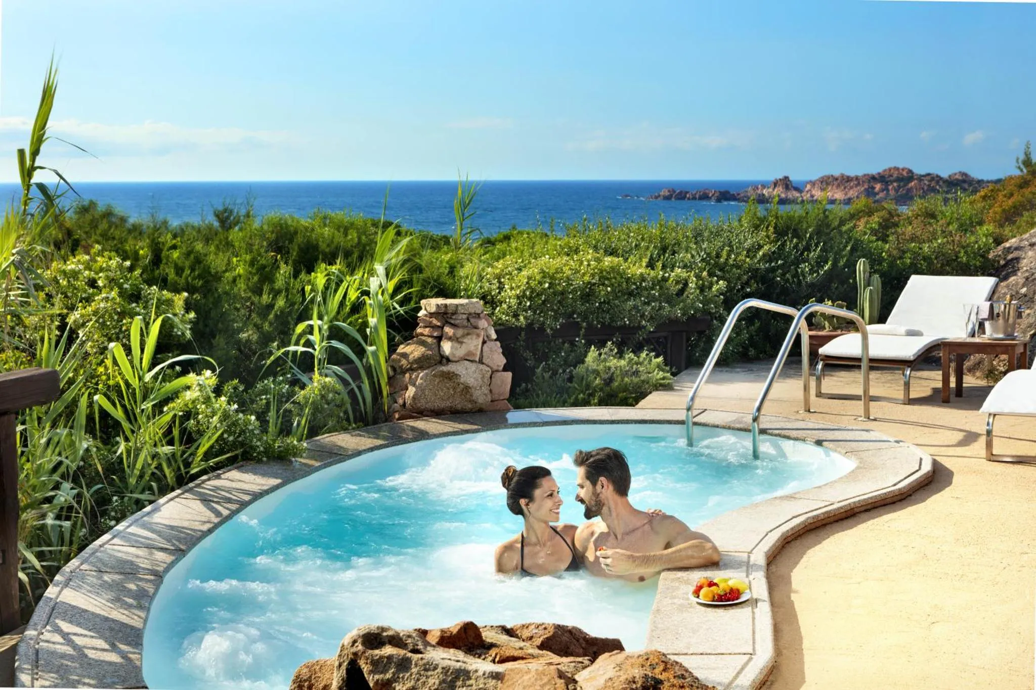Un couple se détend dans un jacuzzi extérieur avec vue sur la mer.