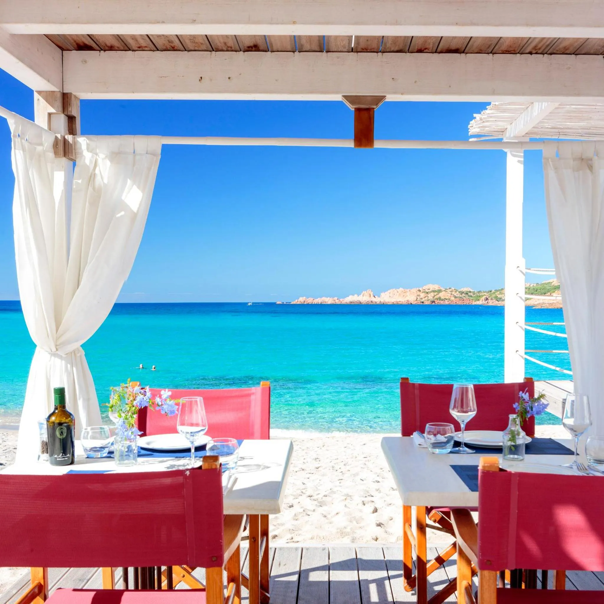 Une table est dressée sur une terrasse face à la mer.