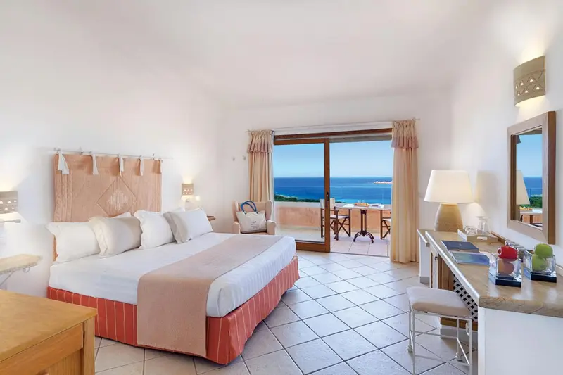 Chambre lumineuse avec un grand lit et vue sur la mer.
