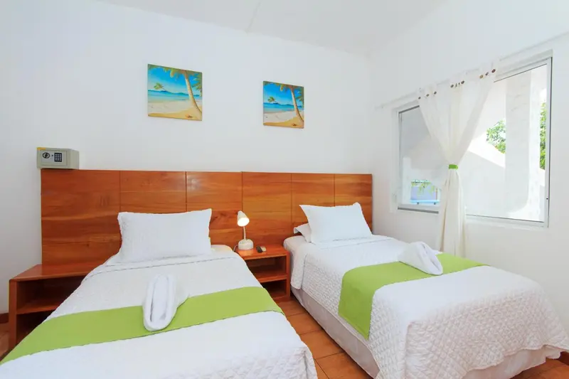Une chambre lumineuse avec deux lits simples et une décoration murale sur le thème de la plage.
