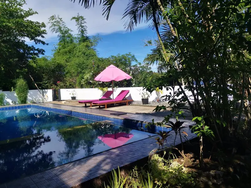 Une piscine rectangulaire bordée d'une terrasse ensoleillée avec des transats roses.