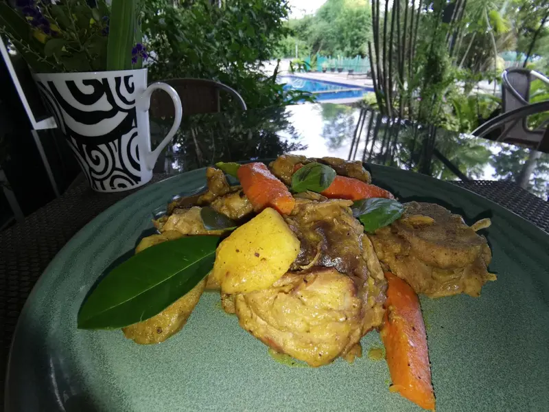 Assiette de poulet au curry avec des légumes et une boisson décorée.