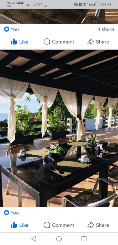 Une table est dressée sous une pergola ombragée avec vue sur la végétation.
