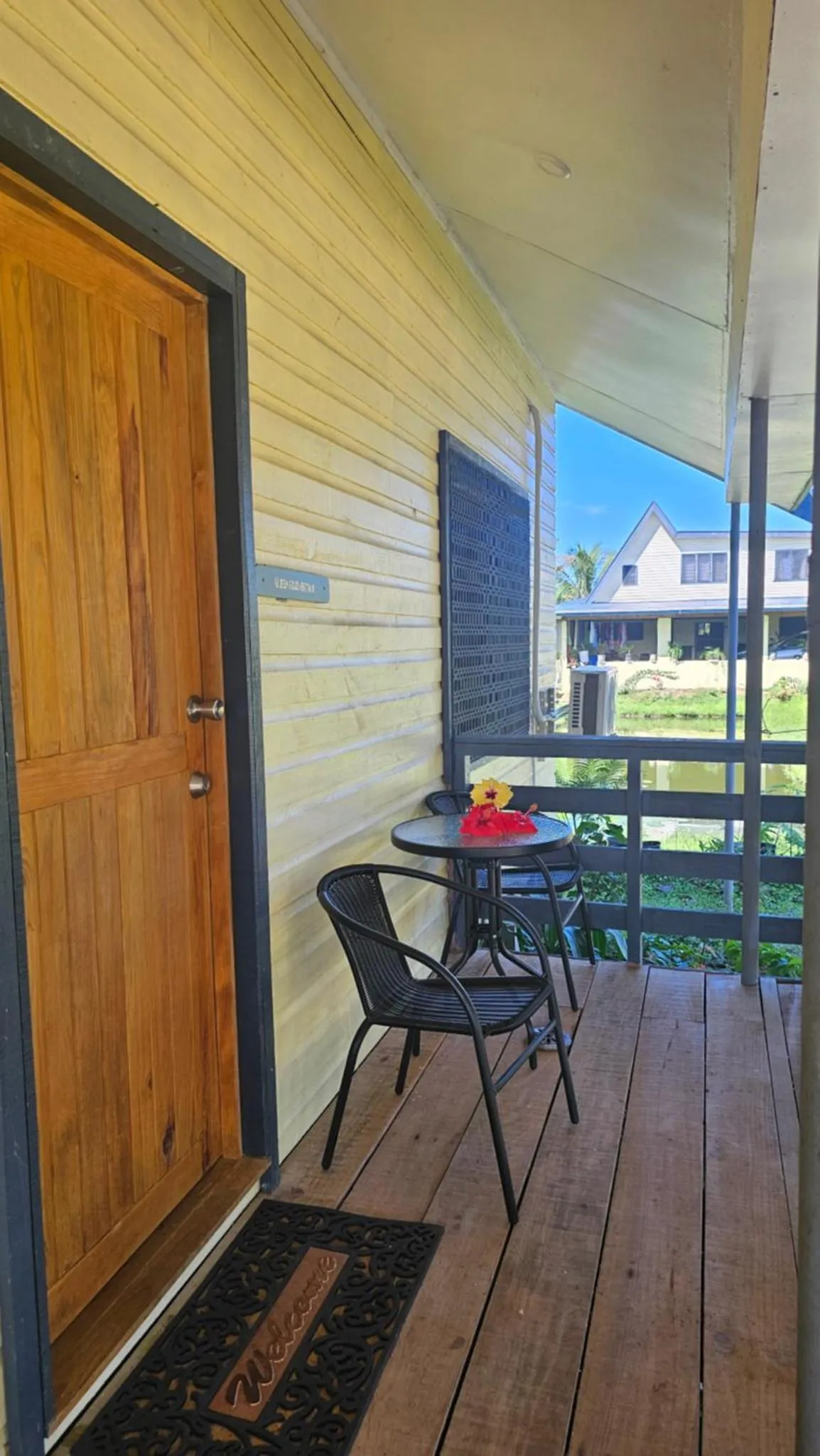 Une petite table et deux chaises se trouvent devant une porte en bois sur une terrasse.