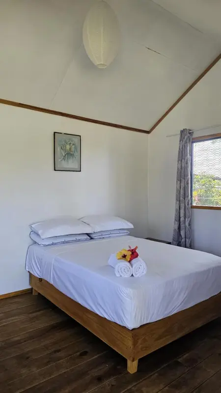 Une chambre lumineuse avec un lit recouvert de draps blancs et décoré de fleurs.
