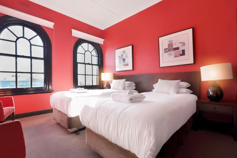 Une chambre lumineuse avec un grand lit et des murs rouges.