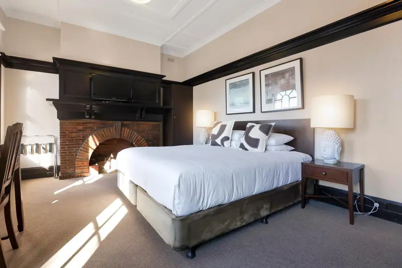 Une chambre lumineuse avec un grand lit et une cheminée.