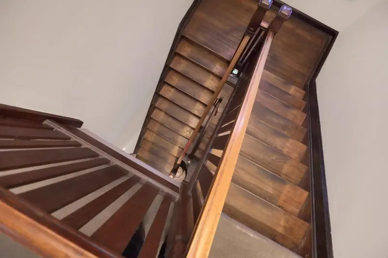 Escalier en bois sombre montant vers le second étage.