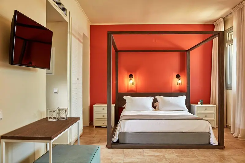 Une chambre avec un lit à baldaquin et une télévision murale.