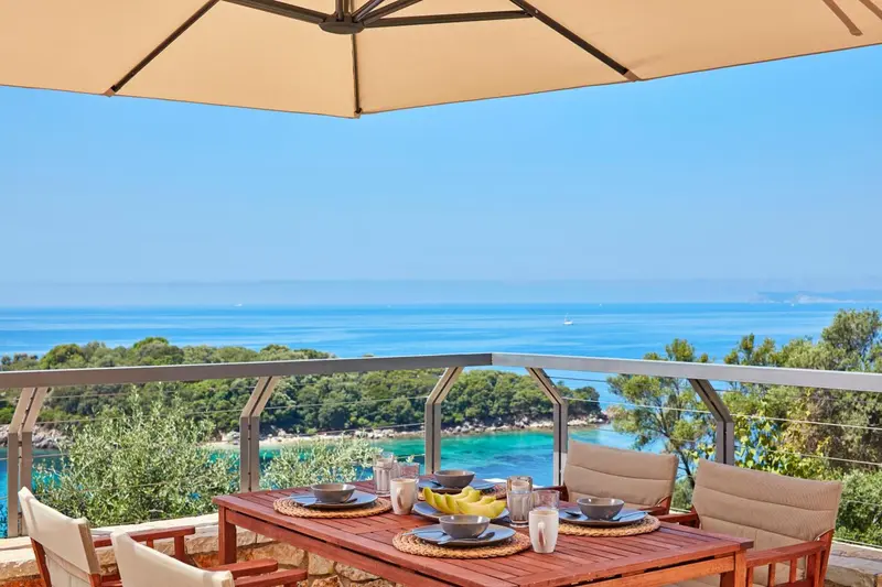 Une table est dressée sur une terrasse avec vue sur la mer.