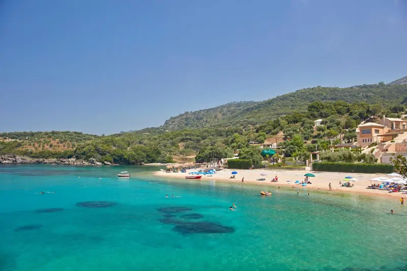 Une plage de sable fin bordée d'une eau turquoise et d'une végétation luxuriante.