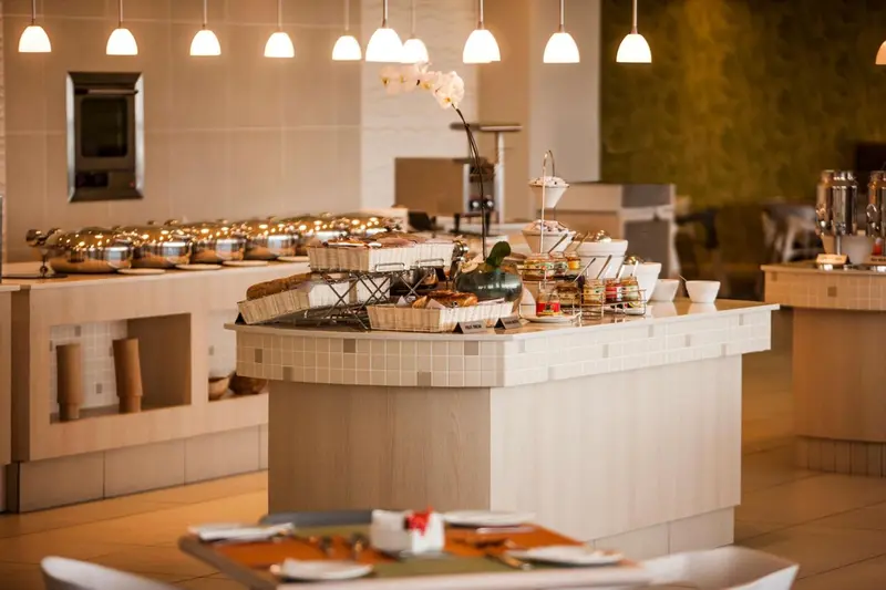 Un buffet propose une variété de plats et de boissons dans une salle lumineuse.