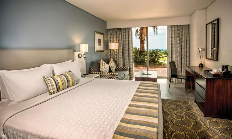 Une chambre lumineuse avec un grand lit et un coin salon.
