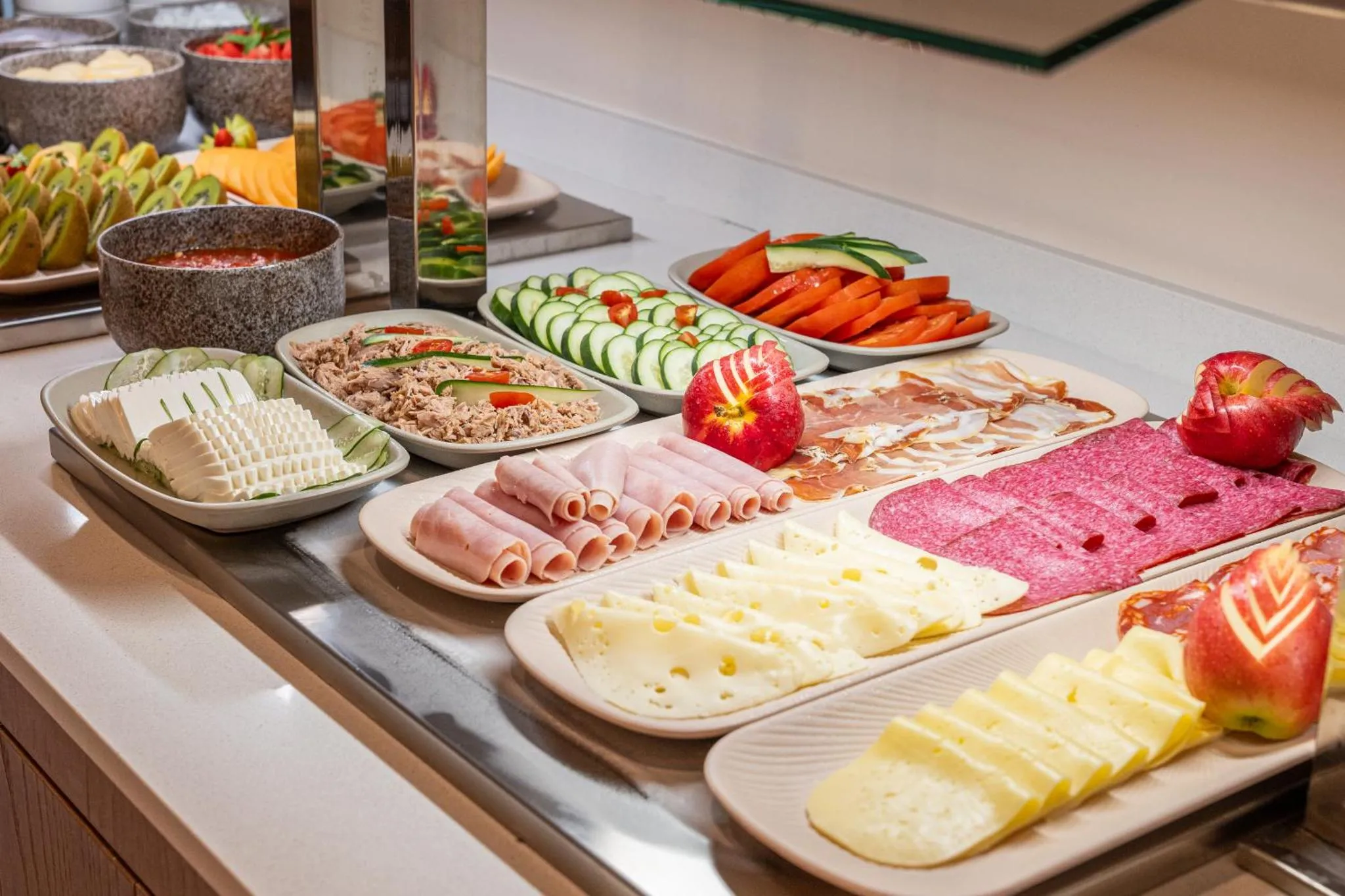 Présentation de crudités et de charcuteries sur un buffet.