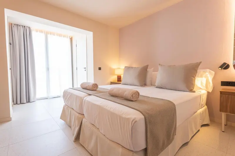 Une chambre lumineuse avec un grand lit et un accès à une terrasse.