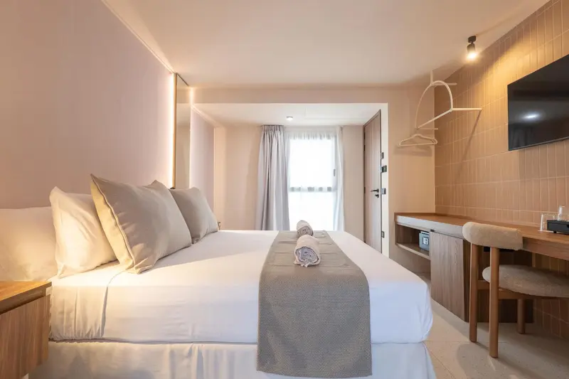 Une chambre lumineuse avec un grand lit et un bureau en bois.