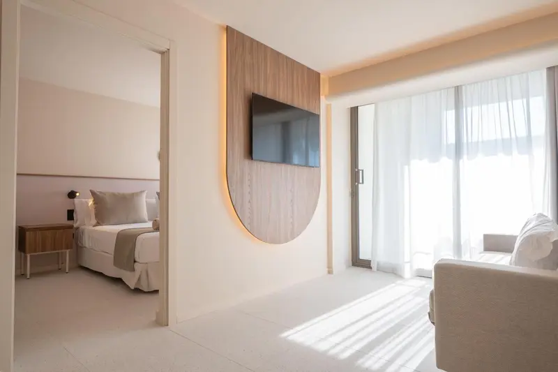 Une chambre lumineuse s'ouvre sur un espace salon avec canapé.