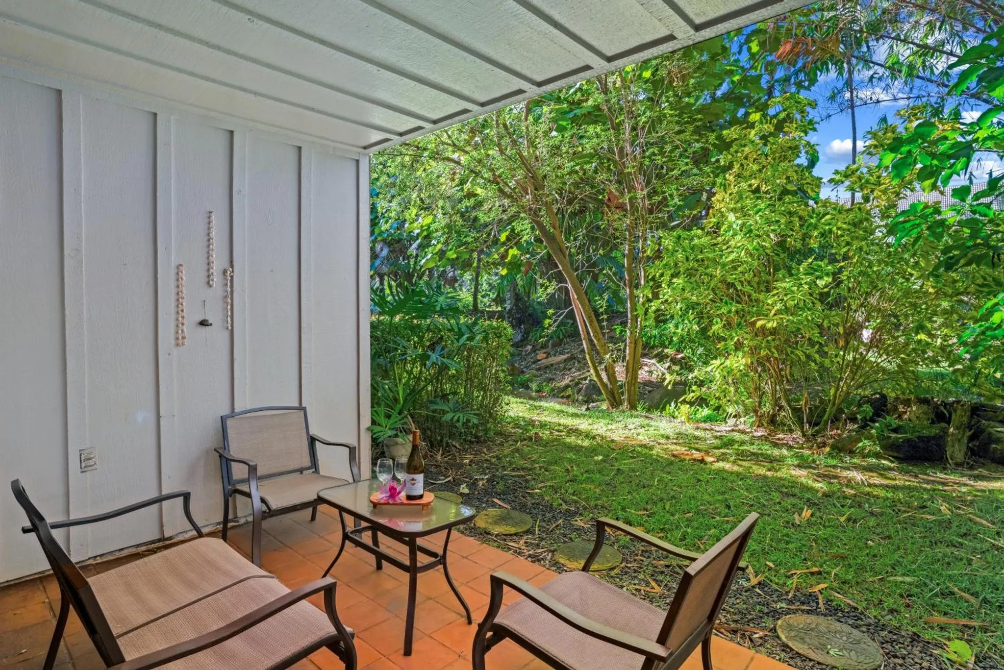Terrasse ombragée avec mobilier de jardin donnant sur une végétation luxuriante.