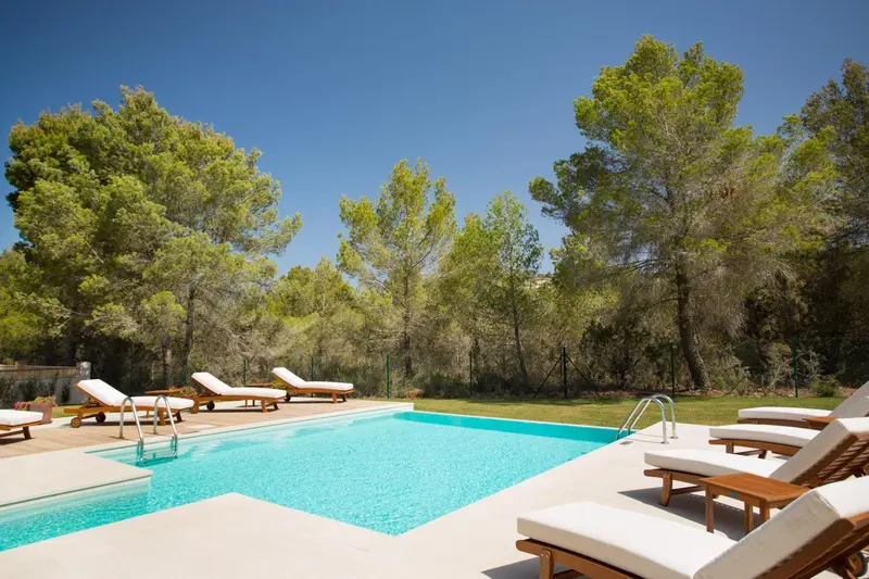 Transats alignés au bord d'une piscine turquoise dans un cadre verdoyant.