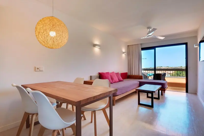 Espace de vie lumineux avec table à manger et canapé près d'une baie vitrée.