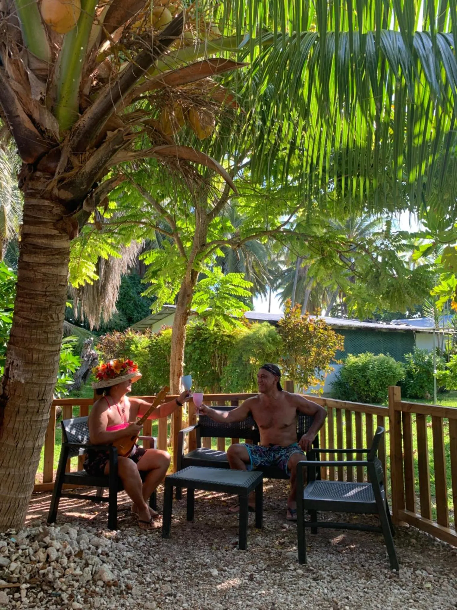 Deux personnes sont assises à une table dans un jardin ombragé.