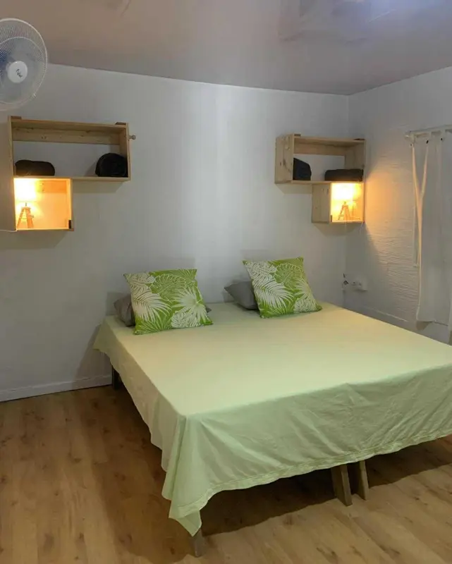 Une chambre lumineuse avec un lit double et des étagères murales.
