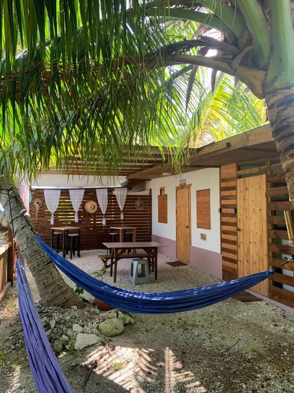 Un espace extérieur ombragé avec une hamac et des tables.