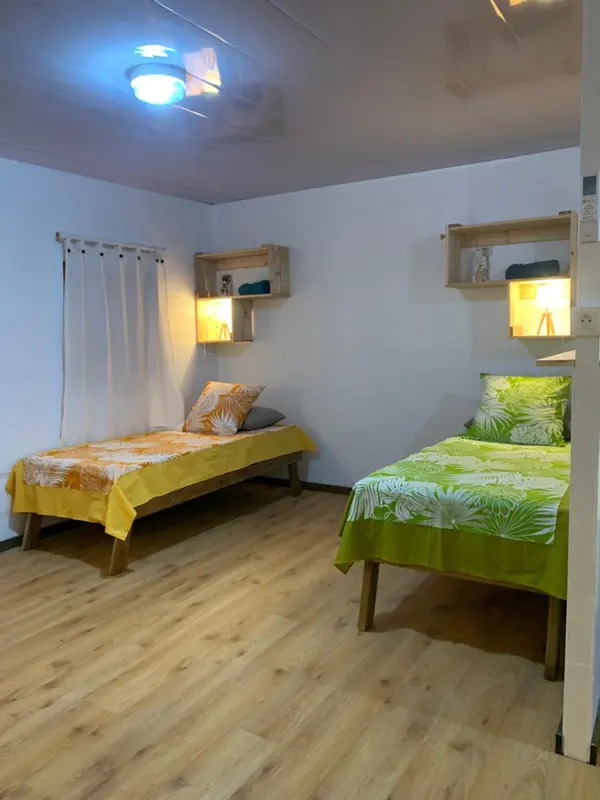 Une chambre lumineuse avec deux lits simples et des étagères murales.