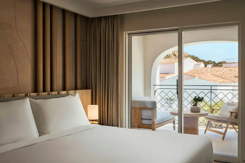 Une chambre lumineuse s'ouvre sur une terrasse avec vue sur les toits.