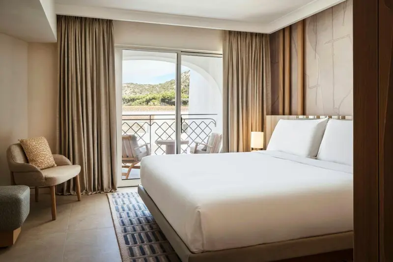 Une chambre lumineuse avec un grand lit et un balcon.