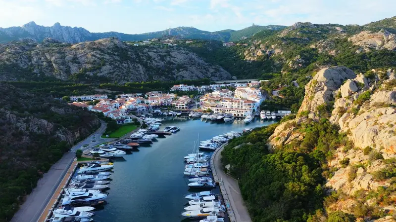 Vue aérienne d'un port de plaisance niché entre des collines rocheuses et la mer.