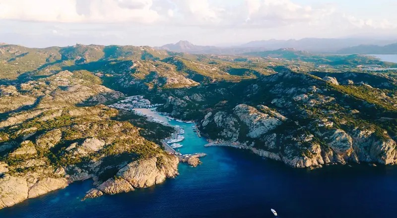 Vue aérienne d'une côte rocheuse avec une baie et des bateaux amarrés.