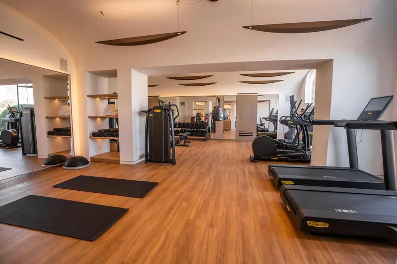 Une salle de sport lumineuse avec des équipements de fitness et un sol en bois.