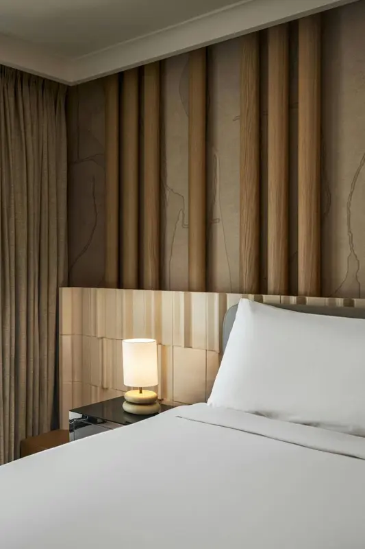 Un lit avec oreillers blancs dans une chambre décorée de panneaux en bois.