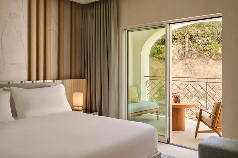 Une chambre lumineuse s'ouvre sur une terrasse avec vue sur la végétation.