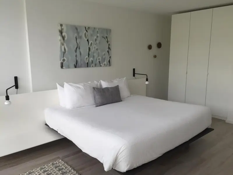 Une chambre lumineuse avec un grand lit recouvert de linge blanc.