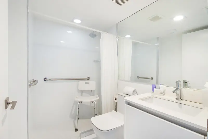 Une salle de bain claire avec douche à siège et lavabo.