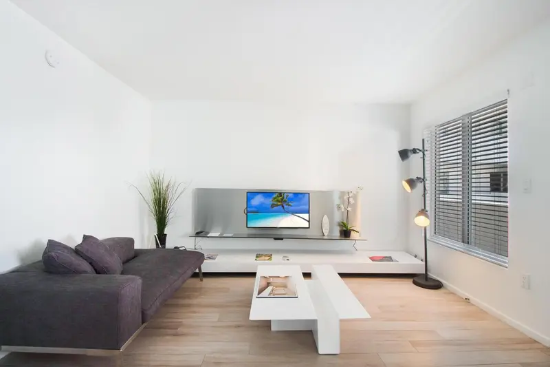 Un salon moderne avec un canapé gris et un meuble bas blanc.