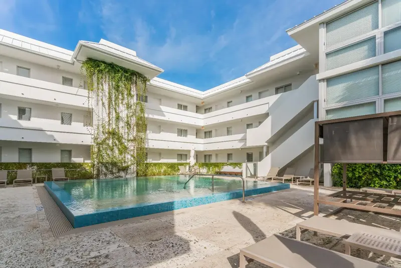 Une piscine rectangulaire au centre d'une cour intérieure d'un bâtiment blanc.