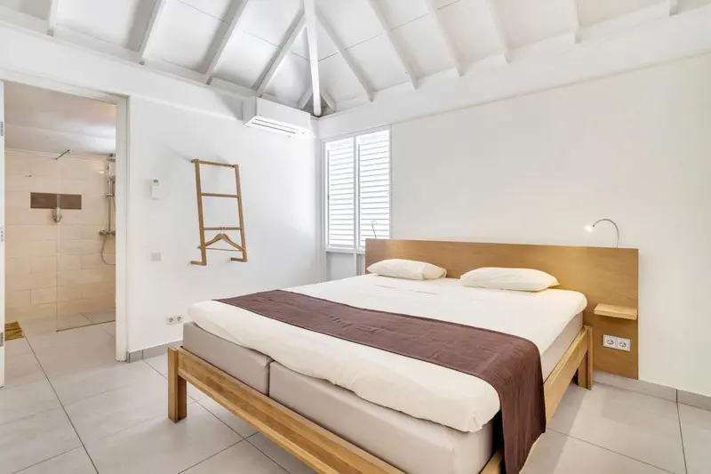 Une chambre lumineuse avec un lit double et un accès à une salle de bain.