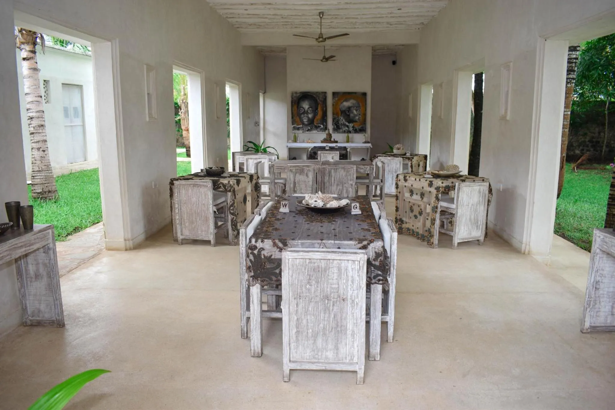 Une salle à manger extérieure avec des tables et des chaises en bois blanchi.