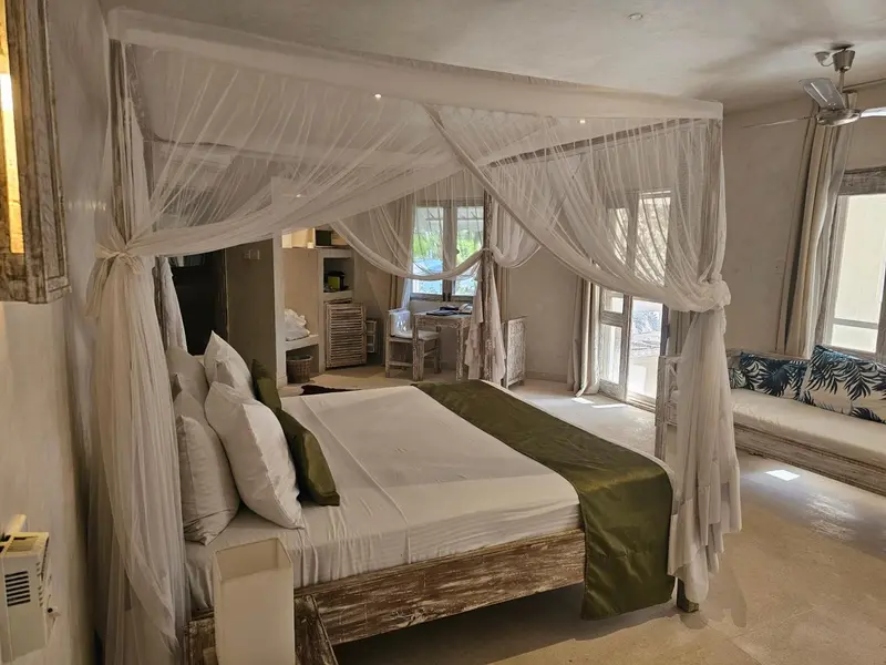 Une chambre avec un grand lit à baldaquin et un coin salon.
