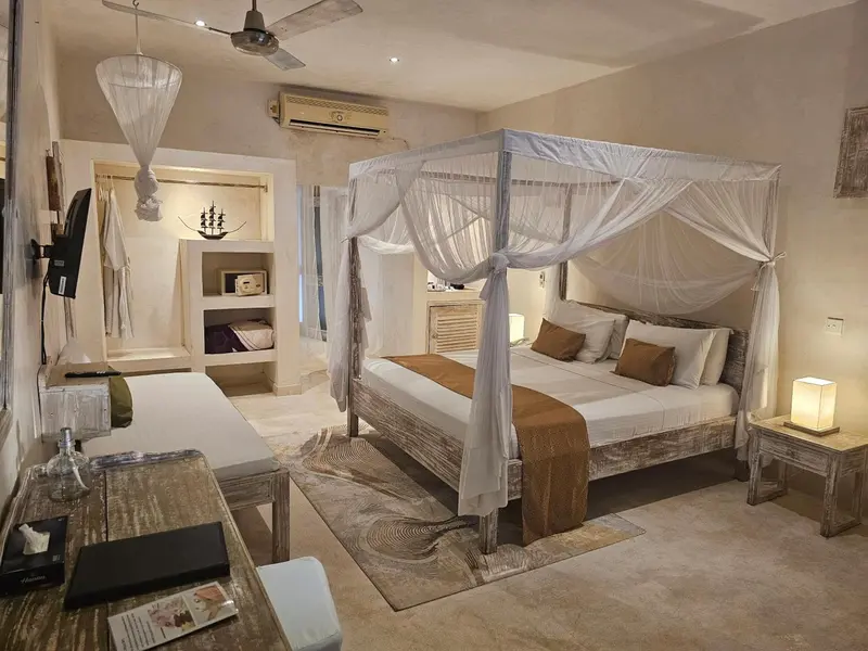 Une chambre lumineuse avec un grand lit à baldaquin et une décoration naturelle.