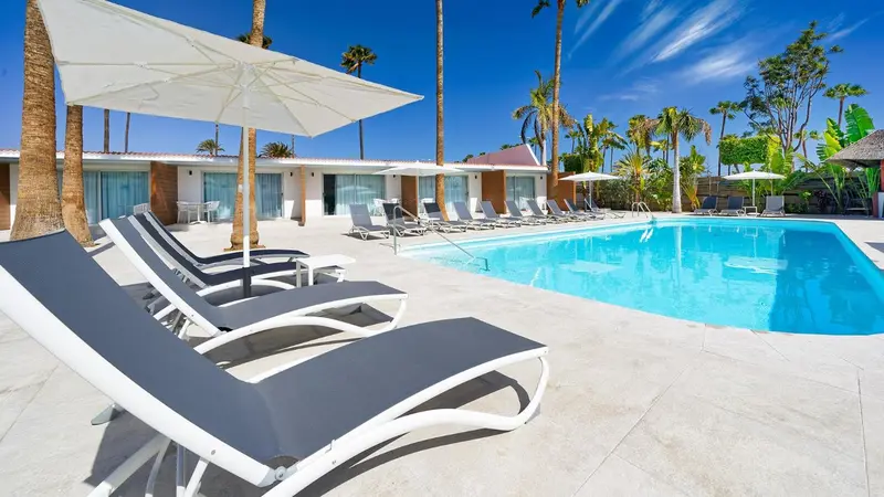 Transats gris et blancs disposés autour d'une piscine ensoleillée.