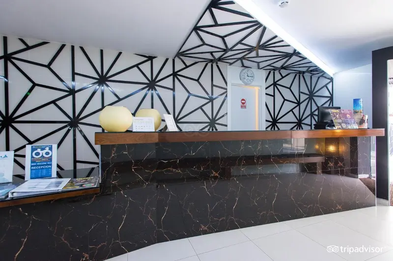 Un comptoir d'accueil moderne avec un mur décoratif géométrique.