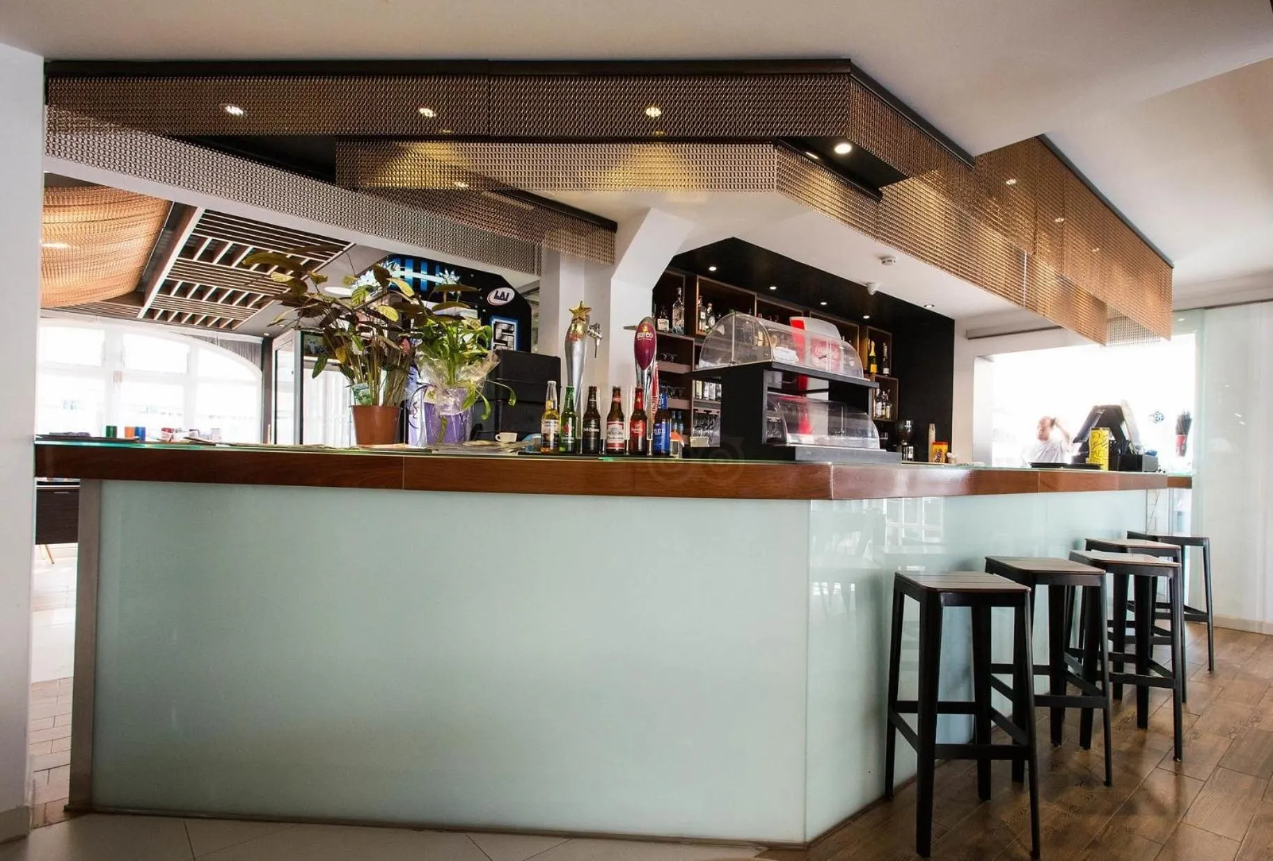 Un comptoir de bar moderne avec des tabourets et des bouteilles exposées.