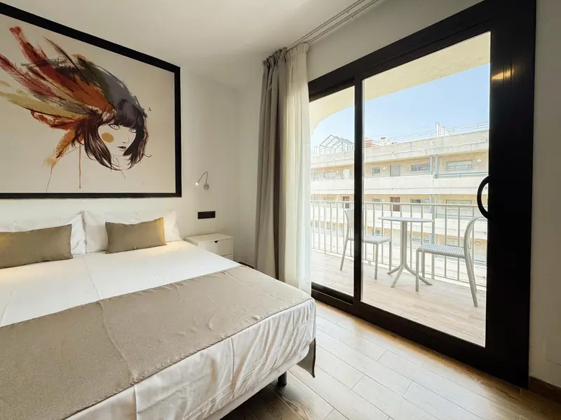 Une chambre lumineuse avec un grand lit et un accès à une terrasse.