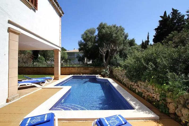 Petite piscine rectangulaire entourée d'un espace dallé avec des transats bleus.