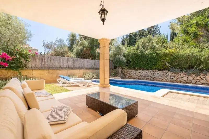 Espace de détente extérieur avec canapés et piscine.